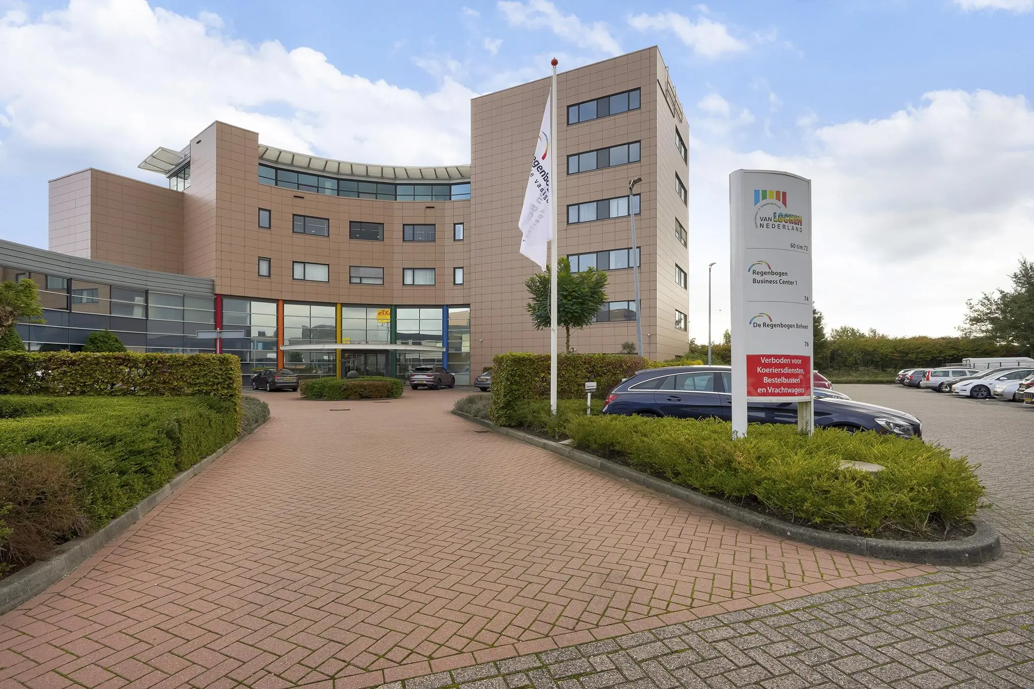 Ingang van het Regenbogen Business Center aan de Laan van ’s-Gravenmade met parkeerplaats en bedrijfsnaambord.